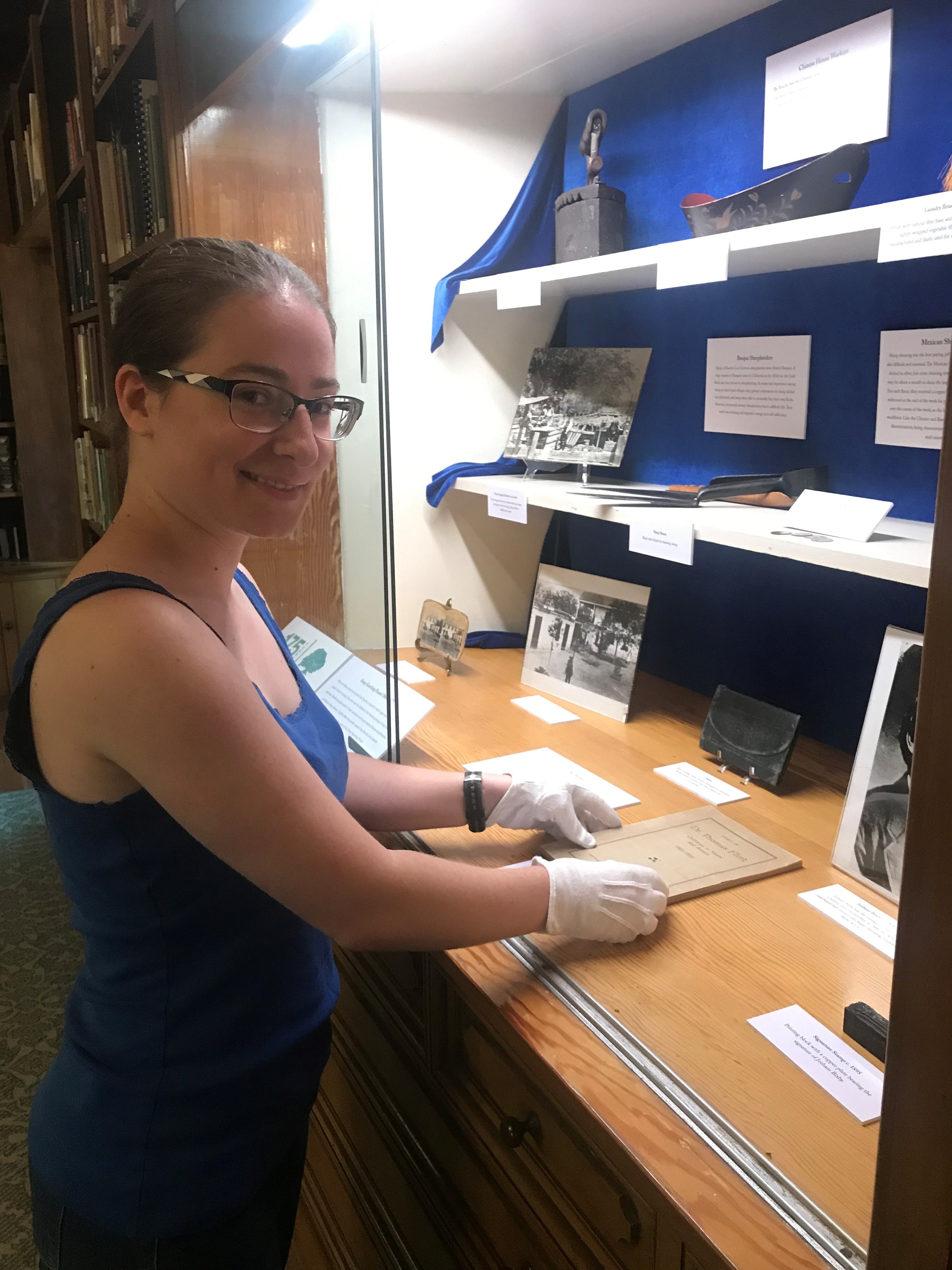 Rancho Los Cerritos' volunteer curatorial intern Nevada Evers installs the latest special exhibit in the library case in commemoration of the 175th anniversary of the adobe's construction (built in 1844) and specifically the sheep ranching years (1866-1890).