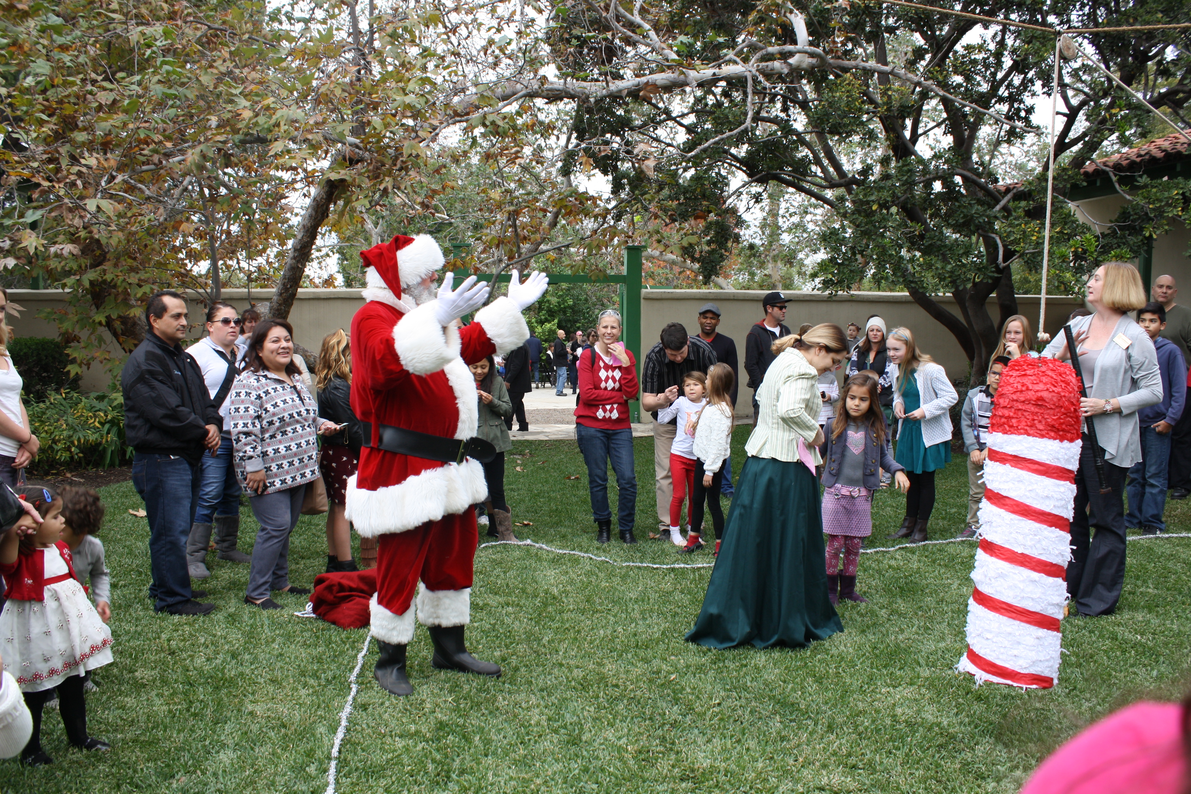 Rancho Los Cerritos hosts its annual "Home for the Holidays" event this year on Sunday, December 8, 2019. (Image - Santa in RLC courtyard w families and kids with a pinata.)