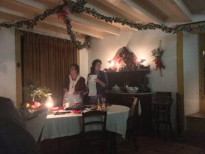 Two women in 1880s outfits prepare for CHristmas in the dining room