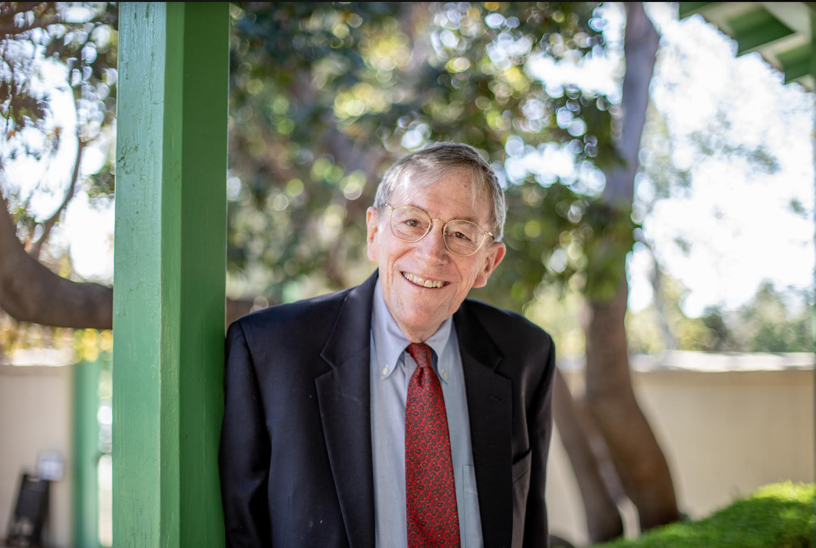 Elderly man in suit smiling outdoors