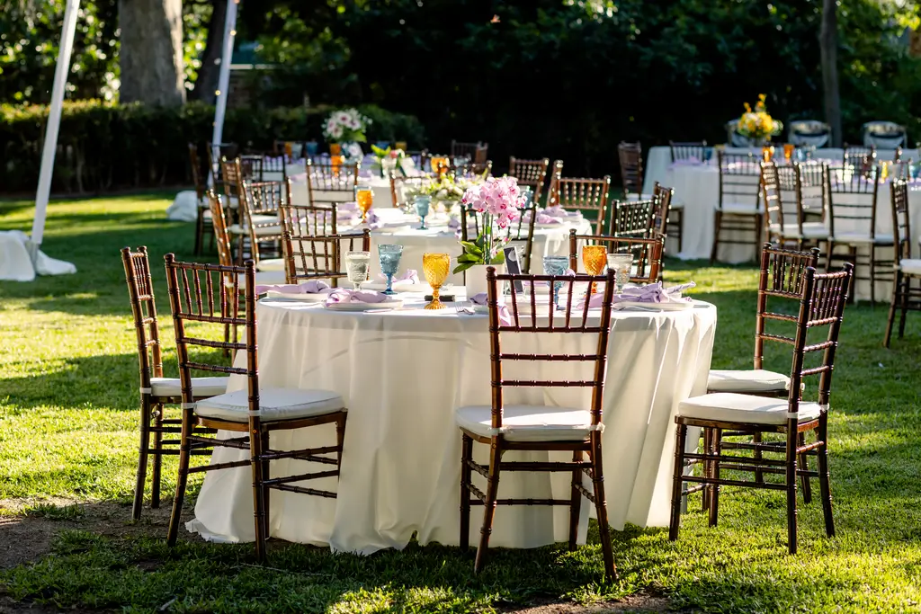 Outdoor wedding reception with round tables and chairs.
