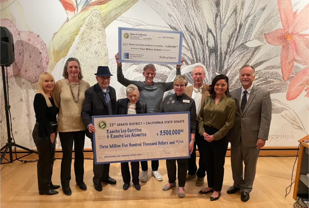 Group holding giant checks for historical site funding.