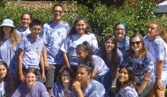 Group of people wearing matching shirts outdoors.