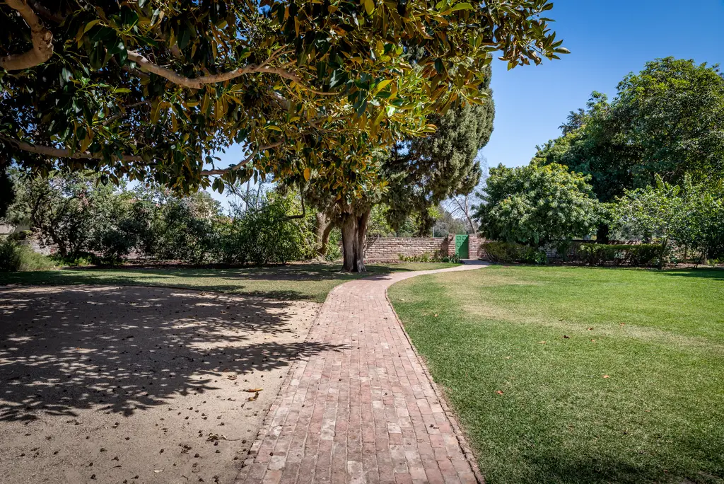 Brick path through green garden under trees.