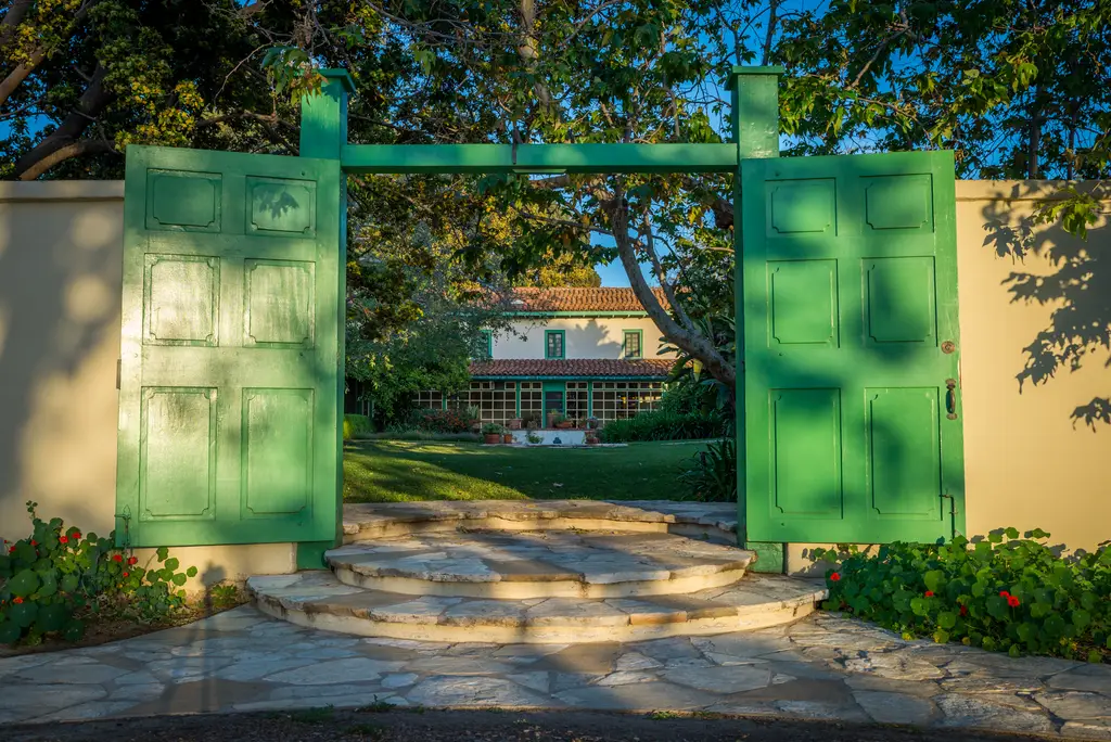 Green gates opening to a garden pathway.