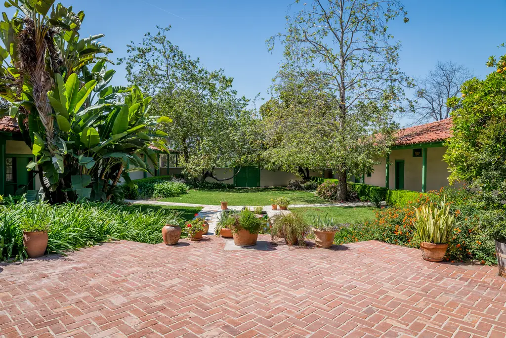 Brick patio with potted plants and green lawn