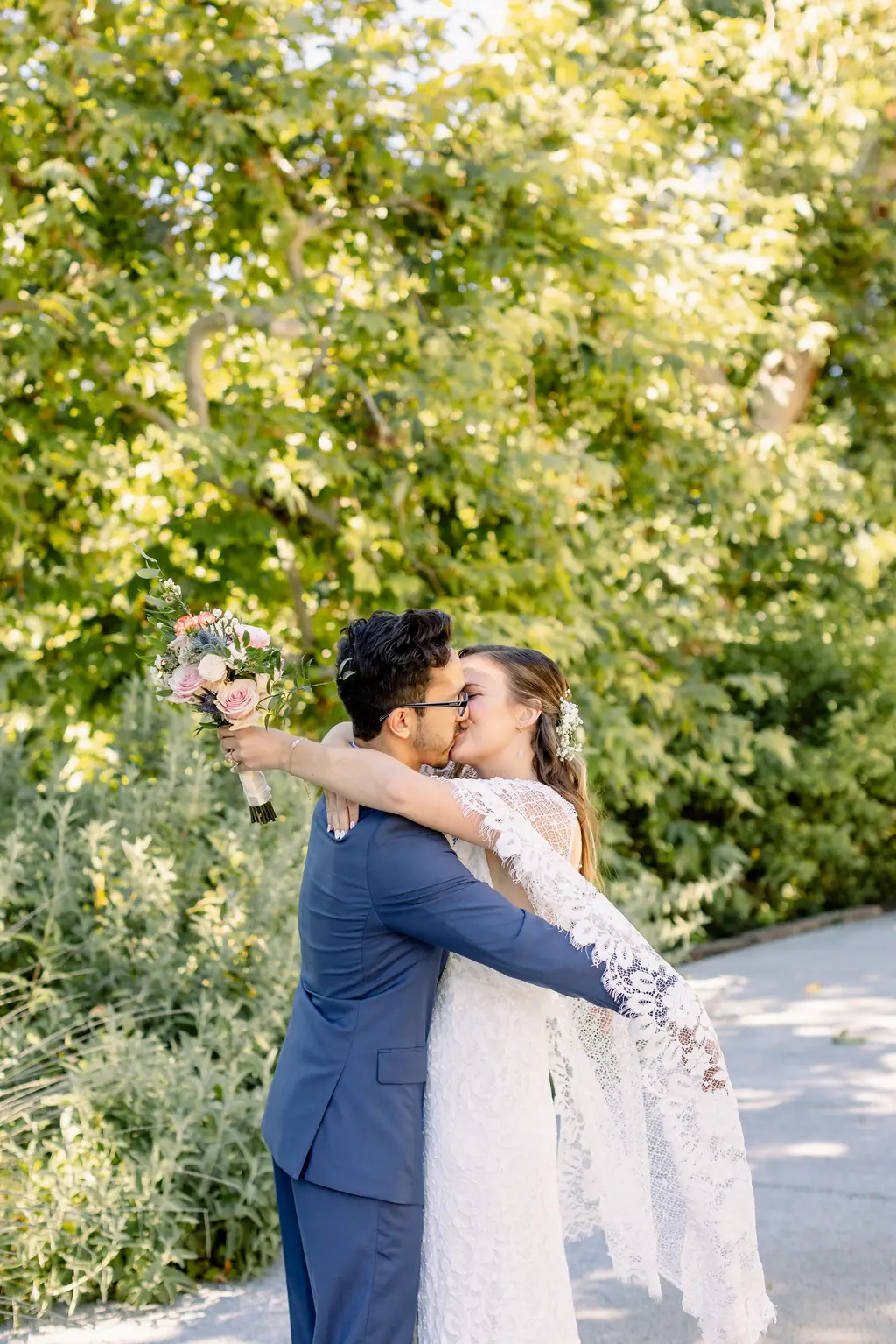 Bride and groom kissing outdoors in sunlight