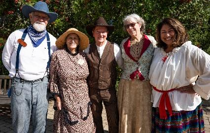 Group in historical attire smiling outdoors.