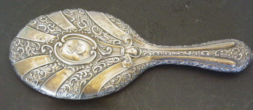 Vintage ornate silver hand mirror with floral design.