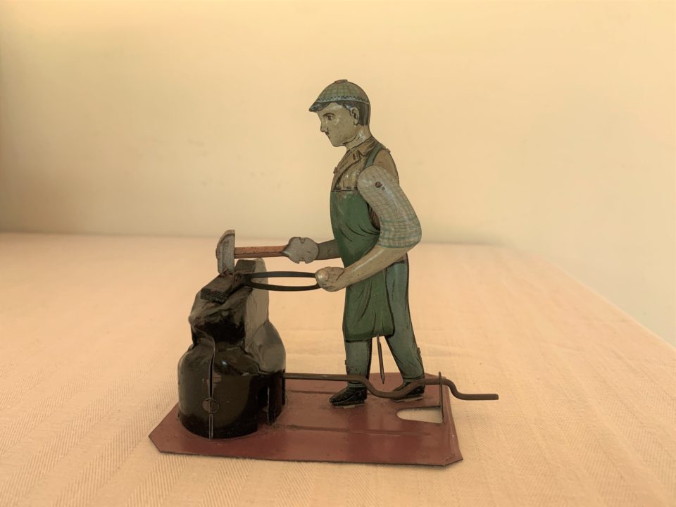Vintage blacksmith toy figure hammering metal