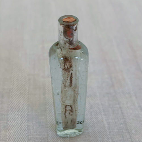 Vintage glass bottle with rusted stopper.