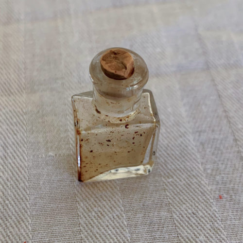 Small glass bottle with cork stopper on cloth surface.