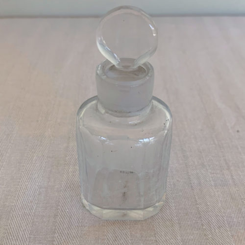 Vintage clear glass perfume bottle with rounded stopper.