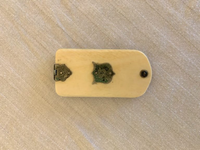 Antique ivory and brass decorative item on fabric