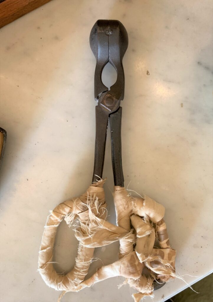 Antique pliers with fabric-wrapped handles.
