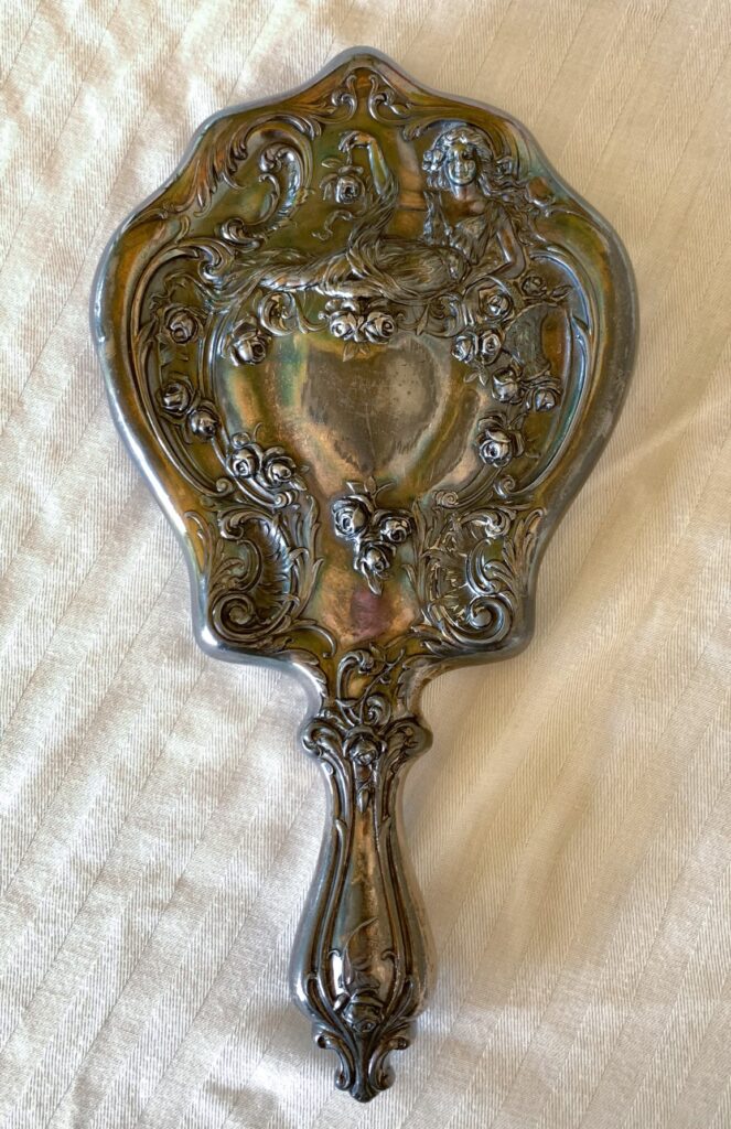 Antique ornate hand mirror with floral design