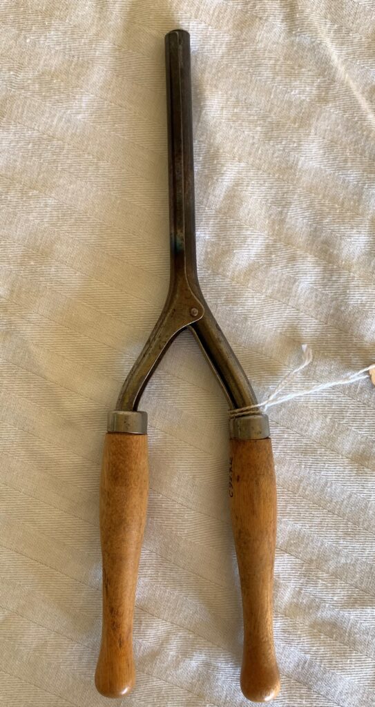 Vintage cherry pitter on white fabric background.