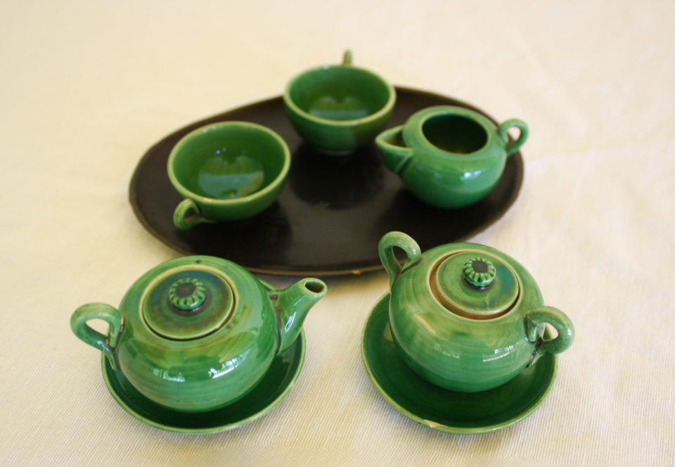 Green ceramic tea set on black tray.