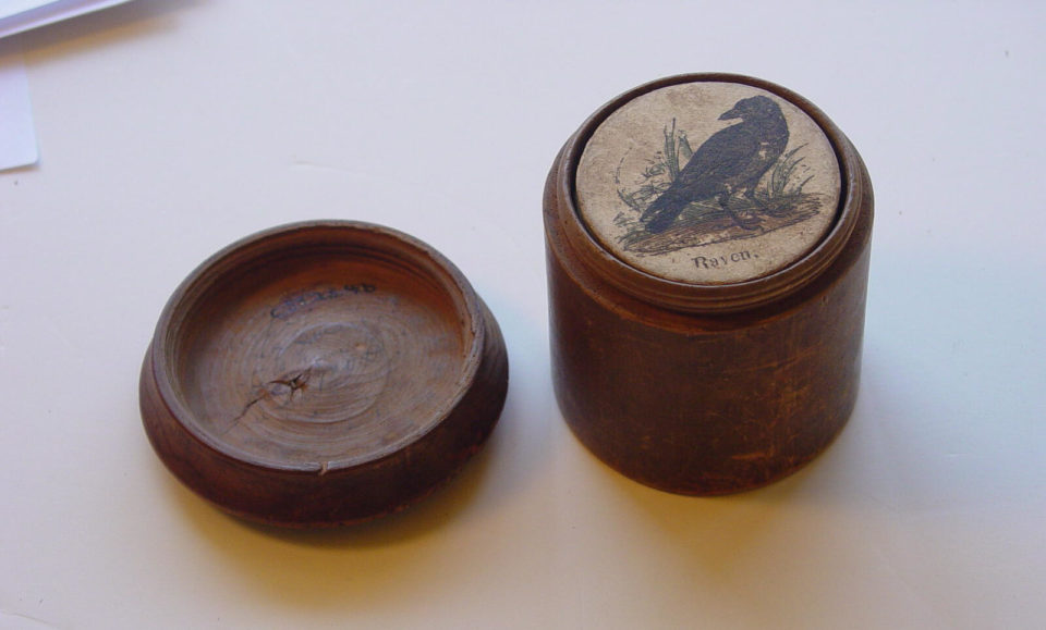 Wooden container with raven illustration on lid.