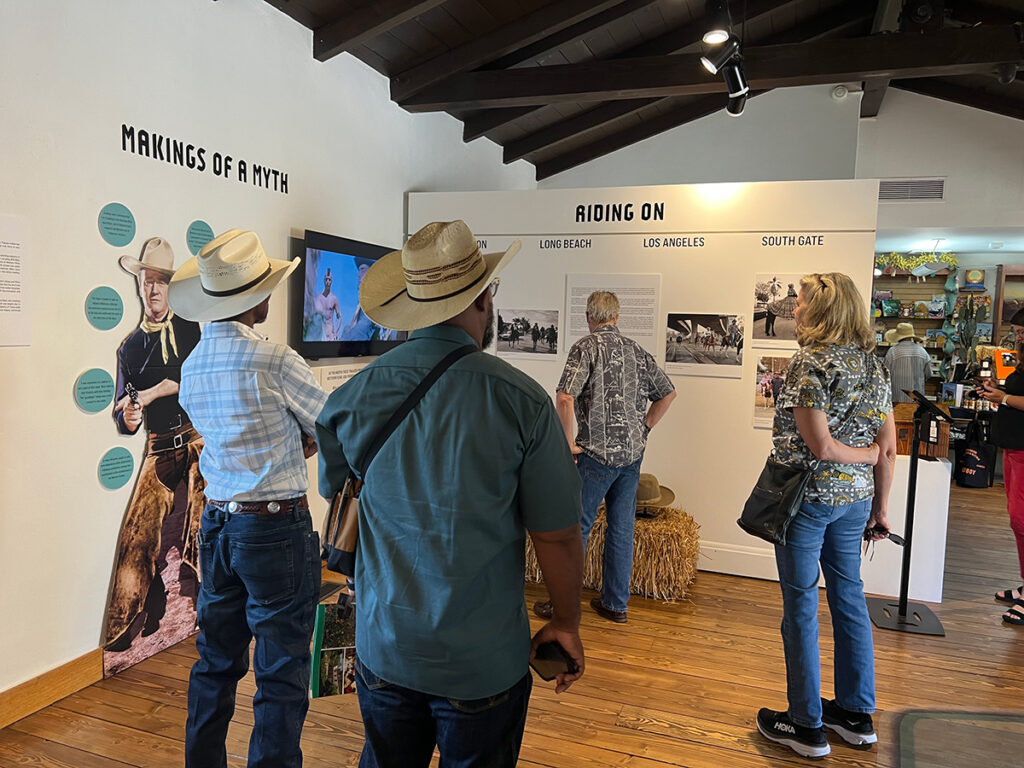 Visitors explore cowboy exhibition at museum.