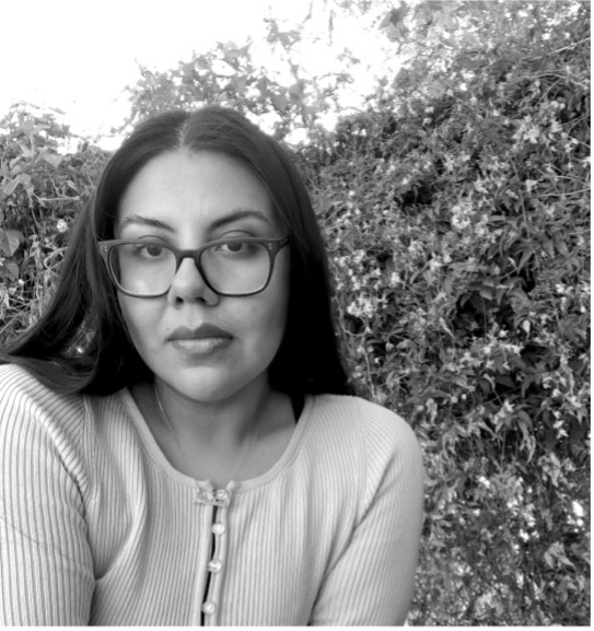 Person with glasses outdoors, black and white photo.