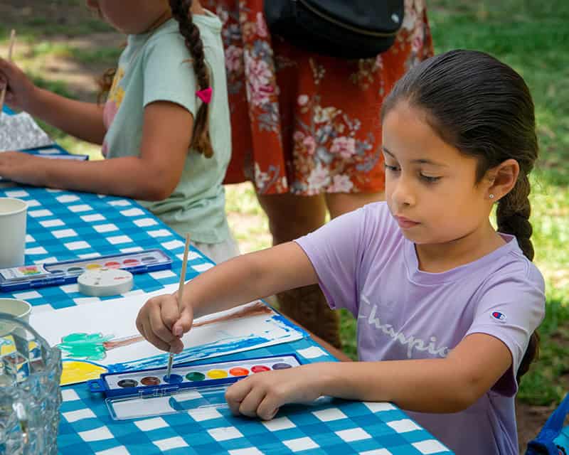 Young girl painting with watercolors outdoors.