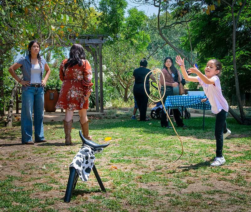 Child plays with lasso at outdoor gathering.