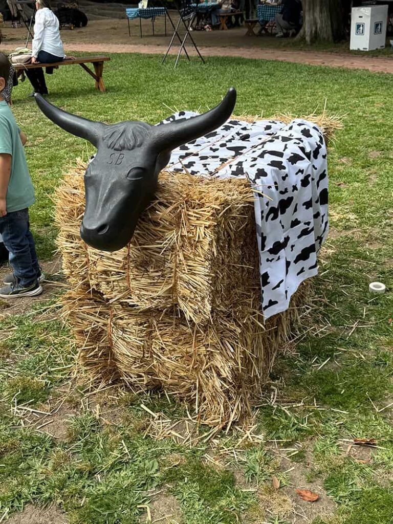 Haystack bull sculpture with black horns outdoors.